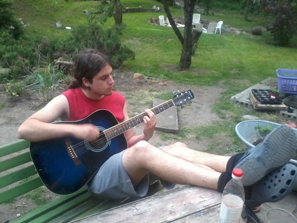 a man playing the guitar in a garden