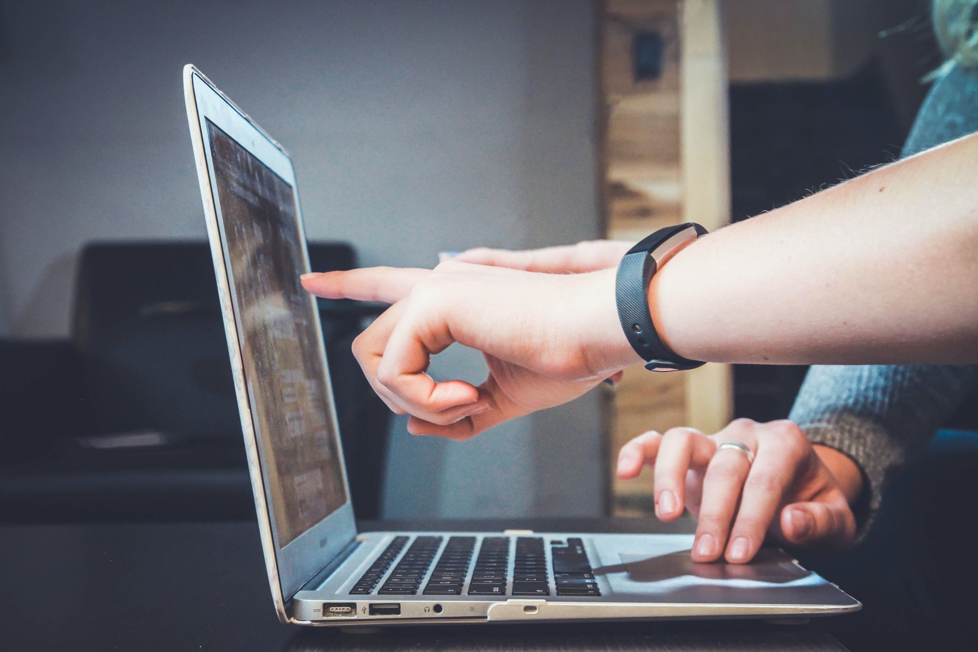 a finger pointing at a computer screen