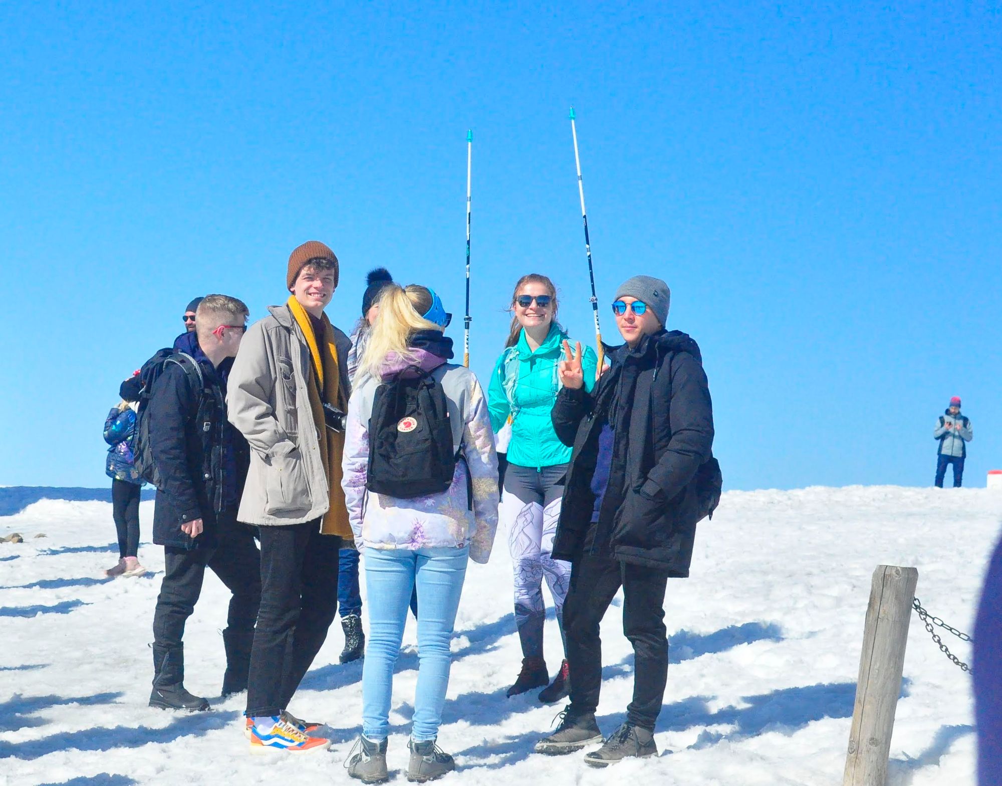 Five Apifiers in mountain gear standing in the snow on top of Sněžka and smiling.